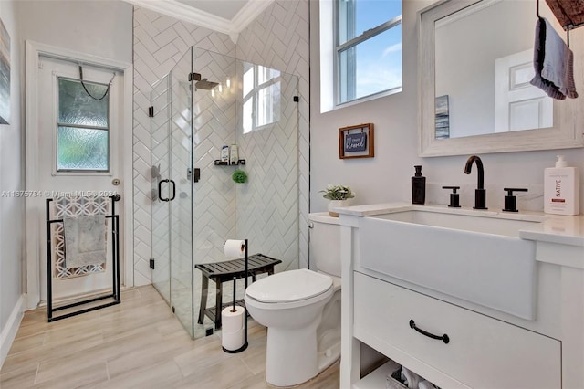 bathroom with wood-type flooring, toilet, ornamental molding, vanity, and an enclosed shower