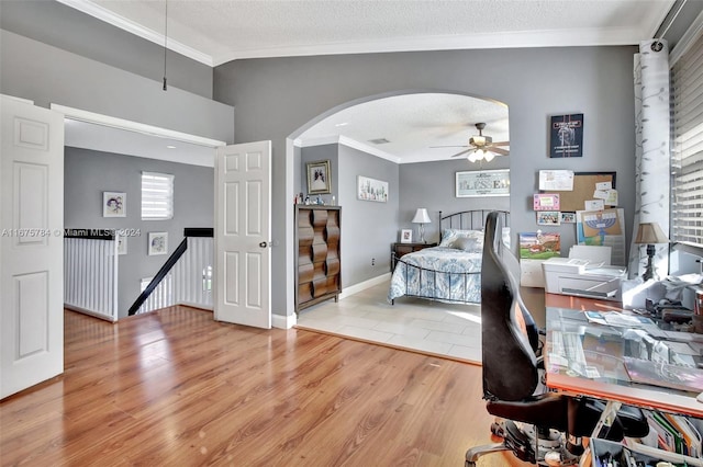 bedroom featuring light hardwood / wood-style floors, crown molding, a textured ceiling, and lofted ceiling