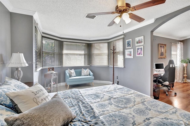 bedroom with ornamental molding, a textured ceiling, wood-type flooring, and ceiling fan