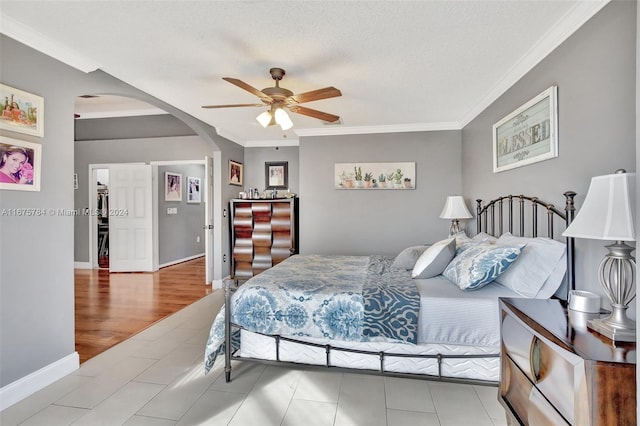 bedroom featuring ceiling fan, crown molding, a textured ceiling, and light hardwood / wood-style floors