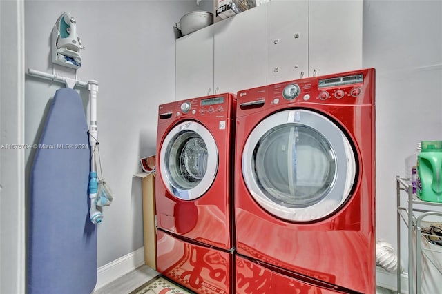 clothes washing area featuring light hardwood / wood-style flooring, independent washer and dryer, and cabinets