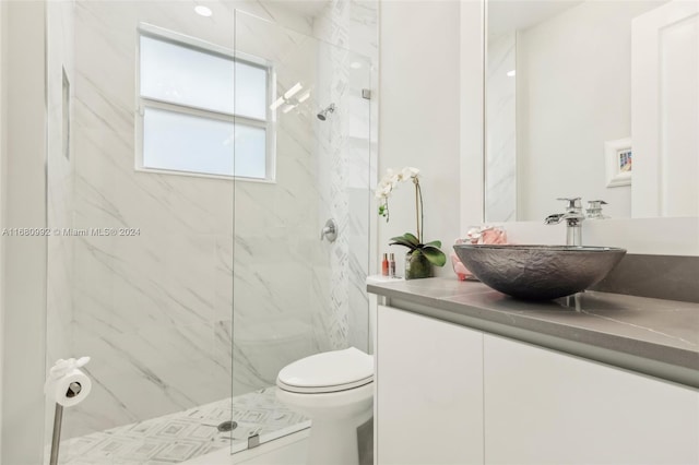 bathroom with vanity, toilet, and tiled shower