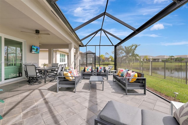 view of patio with a lanai, ceiling fan, a water view, and an outdoor hangout area