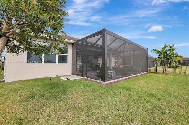 rear view of house featuring a lanai and a lawn