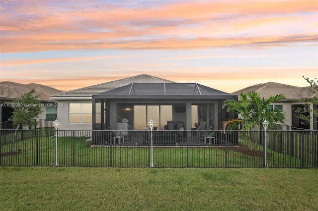 back house at dusk with a lanai and a yard