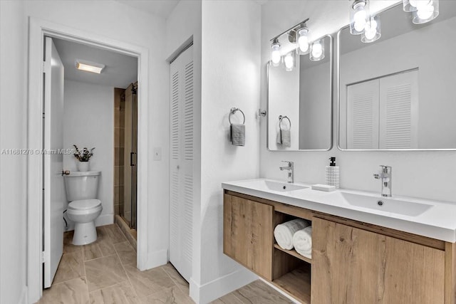 bathroom featuring vanity, a shower with shower door, and toilet