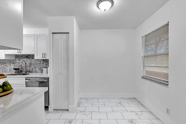 kitchen with sink, white cabinetry, light stone counters, a textured ceiling, and decorative backsplash