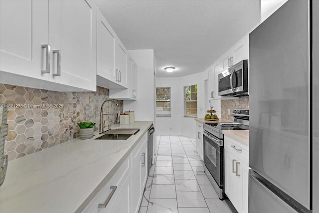 kitchen featuring sink, stainless steel appliances, white cabinets, and light stone countertops