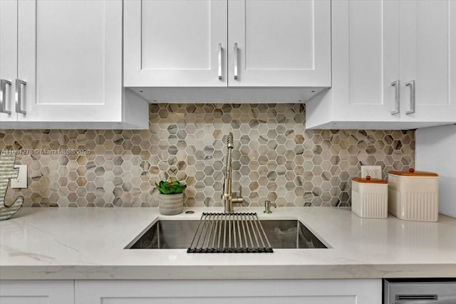 kitchen with light stone counters, sink, decorative backsplash, and white cabinets