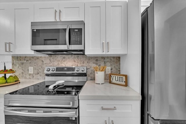 kitchen with appliances with stainless steel finishes, light stone counters, white cabinets, and backsplash