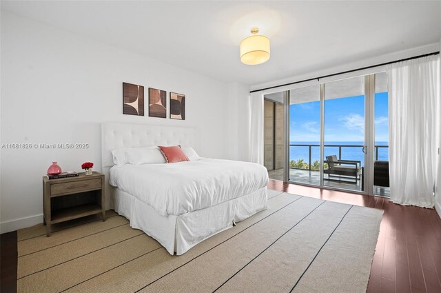 bedroom featuring a water view and dark hardwood / wood-style floors