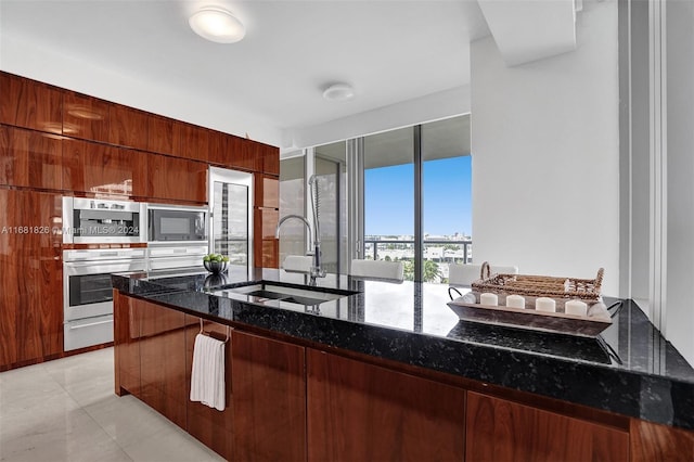 kitchen featuring sink, appliances with stainless steel finishes, light tile patterned flooring, and dark stone countertops