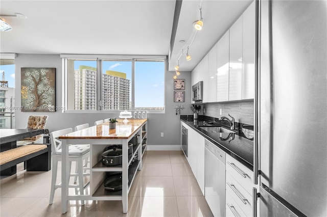 kitchen featuring white cabinets, stainless steel appliances, rail lighting, and sink