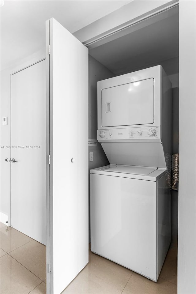 clothes washing area featuring stacked washer and clothes dryer and light tile patterned floors