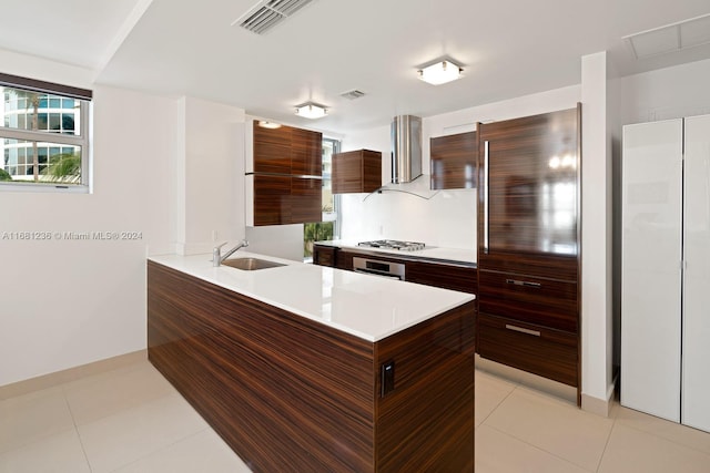 kitchen featuring exhaust hood, kitchen peninsula, sink, light tile patterned floors, and appliances with stainless steel finishes