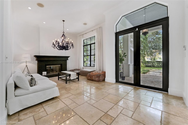 living room with crown molding, a brick fireplace, an inviting chandelier, and plenty of natural light