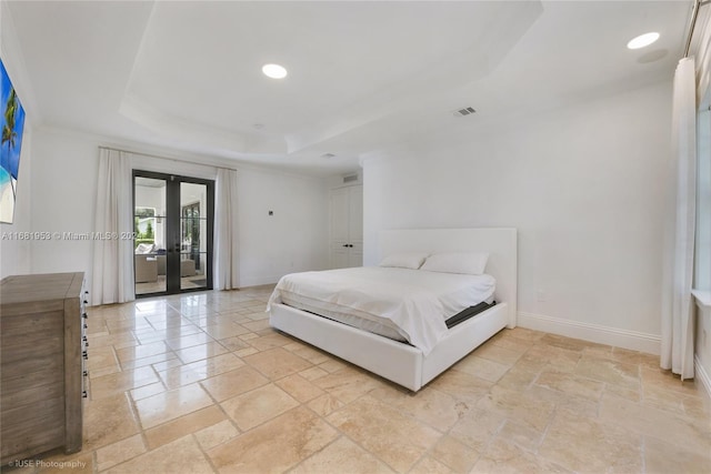 bedroom with french doors, access to outside, and a raised ceiling