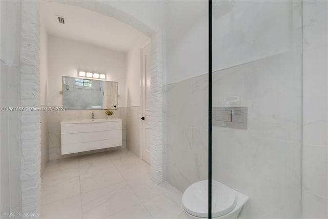 bathroom featuring vanity, toilet, and tile walls