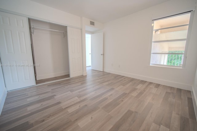 unfurnished bedroom featuring light hardwood / wood-style floors and a closet