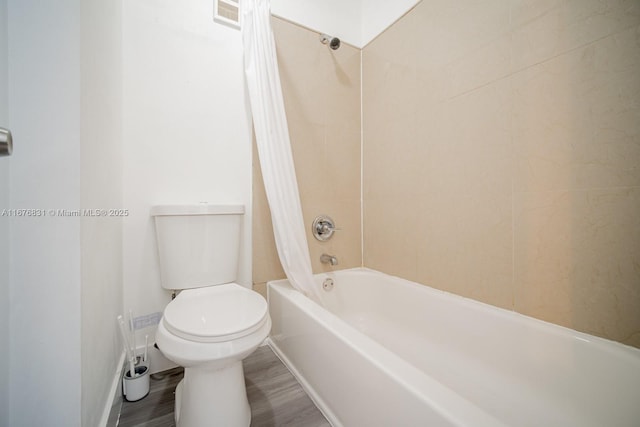 bathroom featuring wood-type flooring, shower / tub combo with curtain, and toilet