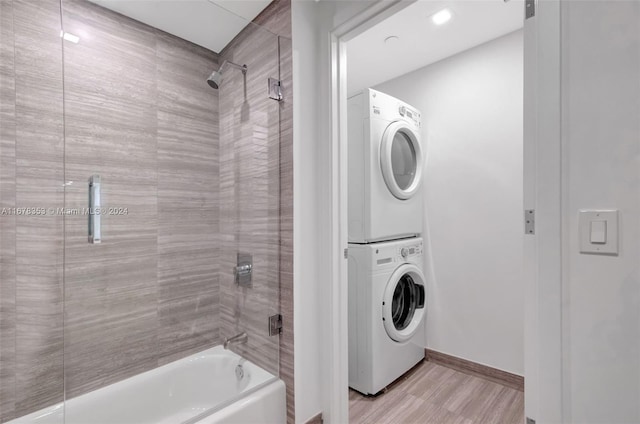 clothes washing area featuring stacked washer and clothes dryer and light wood-type flooring