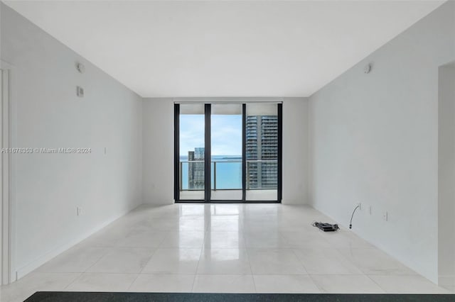 empty room featuring a wall of windows and light tile patterned floors