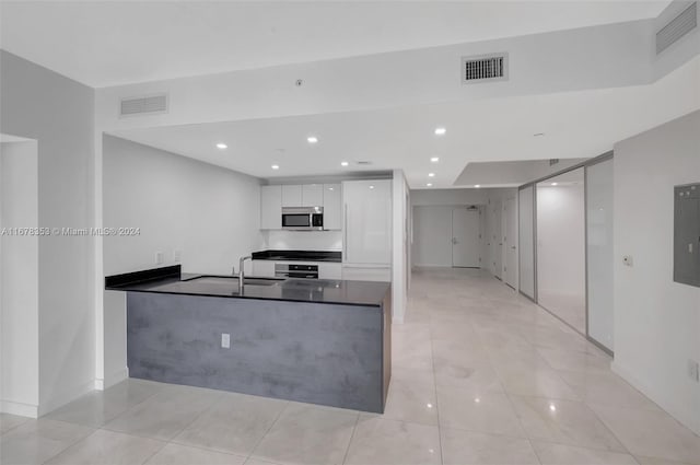 kitchen with sink, white cabinetry, kitchen peninsula, and light tile patterned floors