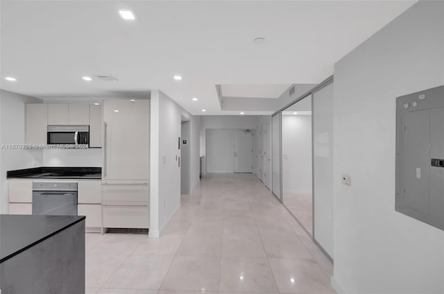 kitchen with appliances with stainless steel finishes, white cabinetry, electric panel, and light tile patterned floors