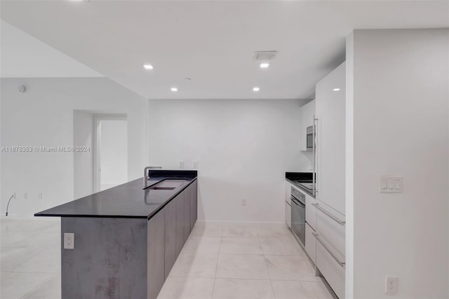 kitchen featuring kitchen peninsula, white cabinets, sink, and light tile patterned floors