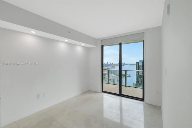 spare room featuring a water view and light tile patterned floors