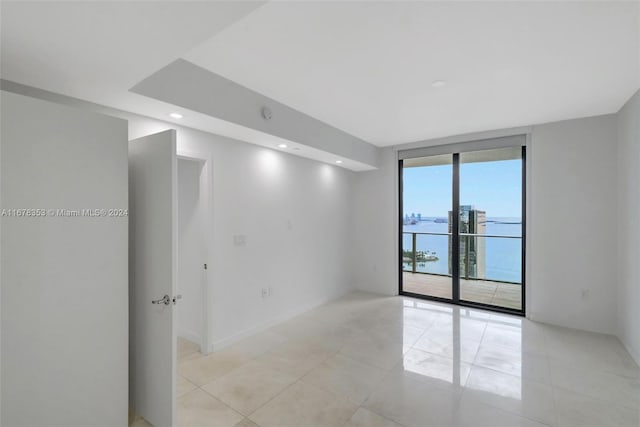 tiled spare room with expansive windows and a water view