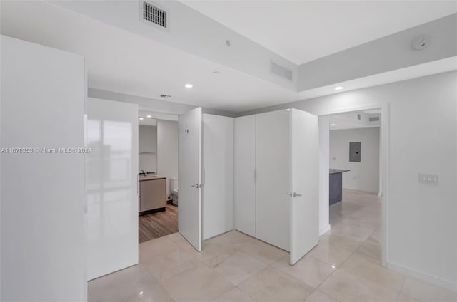 hall featuring light tile patterned flooring and electric panel