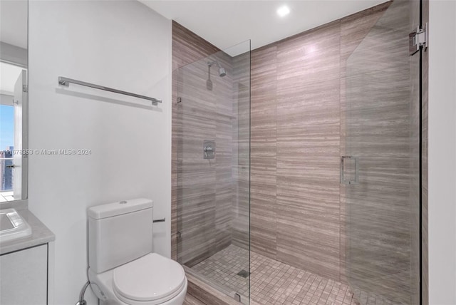 bathroom with toilet, a shower with shower door, and vanity