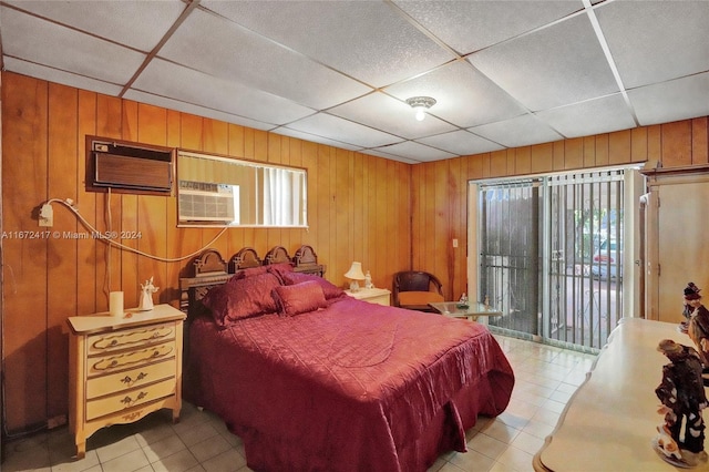 bedroom featuring a drop ceiling, multiple windows, and wood walls