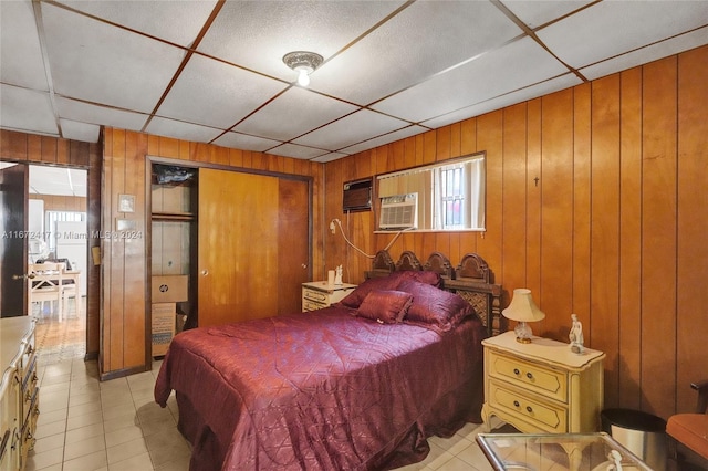 bedroom with a drop ceiling, a closet, and wooden walls