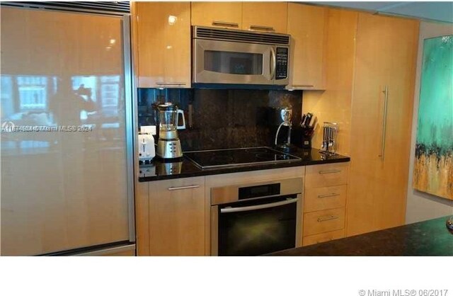 kitchen featuring light brown cabinets, decorative backsplash, and stainless steel appliances