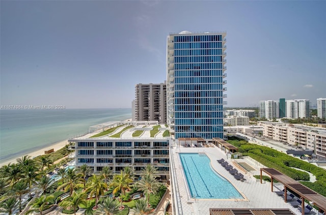 exterior space with a community pool, a water view, and a beach view