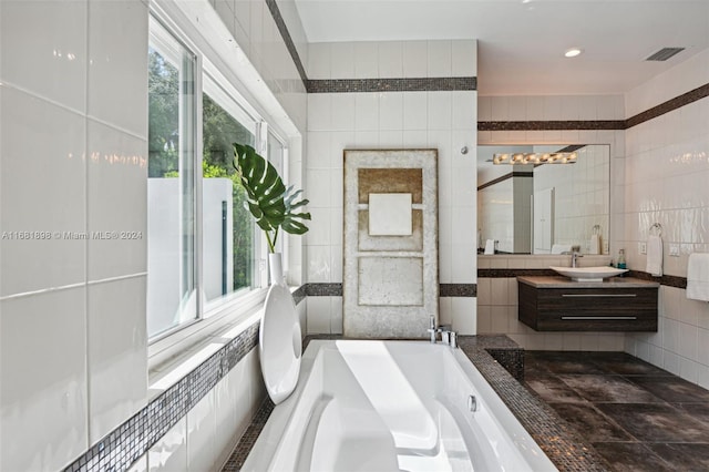 bathroom with vanity, tile walls, and a washtub