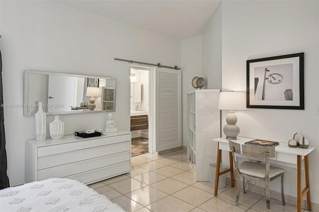 bedroom featuring a barn door, ensuite bath, and light tile patterned floors