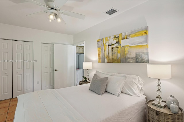 tiled bedroom with two closets and ceiling fan