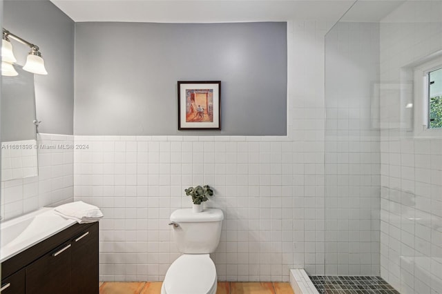 bathroom featuring tile walls, vanity, a tile shower, and toilet