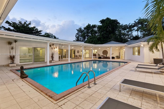 pool at dusk featuring a patio