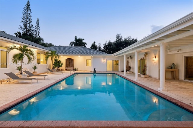 pool at dusk featuring a patio area