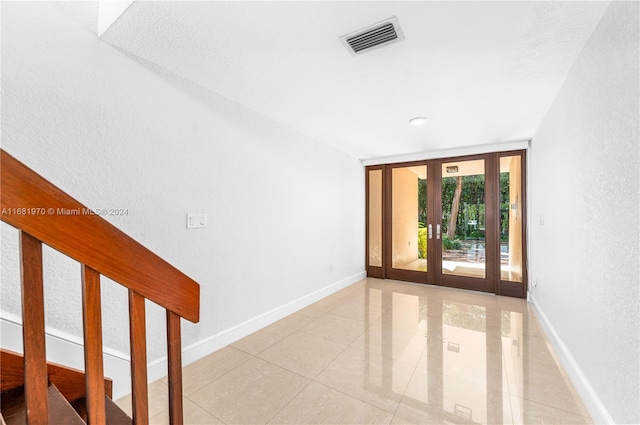 tiled spare room featuring french doors