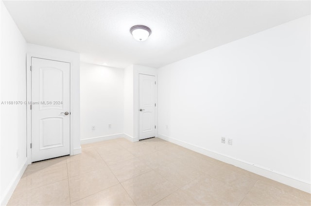 tiled empty room with a textured ceiling