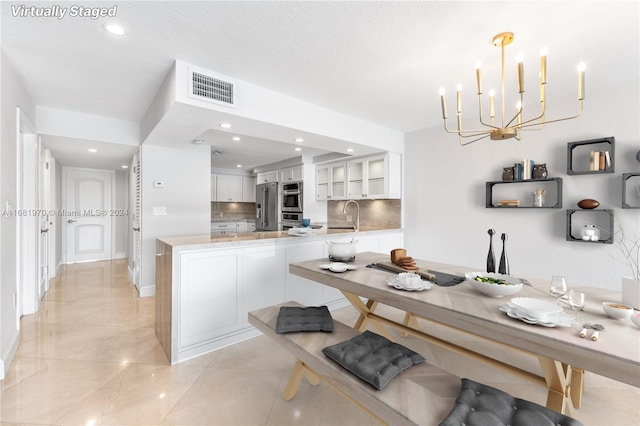 kitchen with kitchen peninsula, sink, pendant lighting, white cabinets, and tasteful backsplash