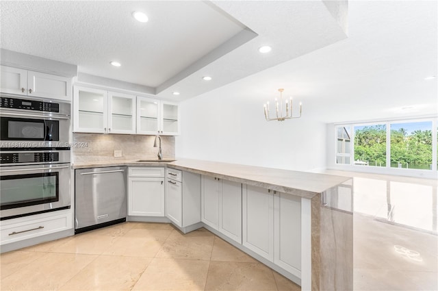 kitchen featuring appliances with stainless steel finishes, white cabinetry, sink, and a tray ceiling