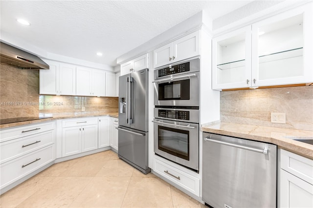 kitchen with white cabinets, light tile patterned floors, backsplash, a textured ceiling, and stainless steel appliances