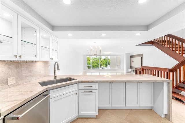 kitchen with dishwasher, sink, a textured ceiling, white cabinets, and a notable chandelier