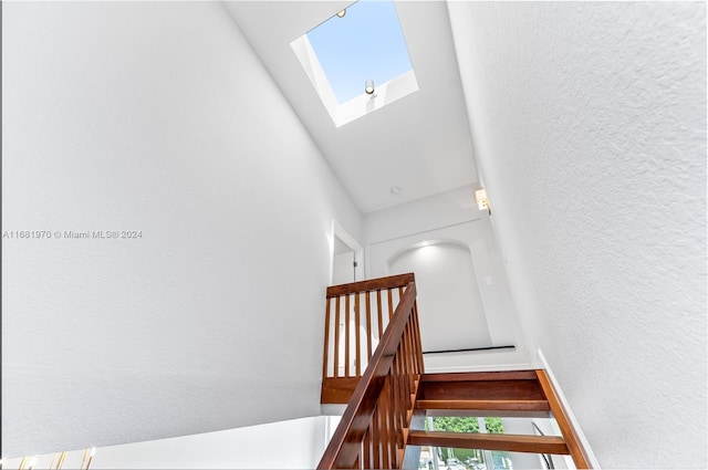 stairs with a high ceiling, a healthy amount of sunlight, and a skylight